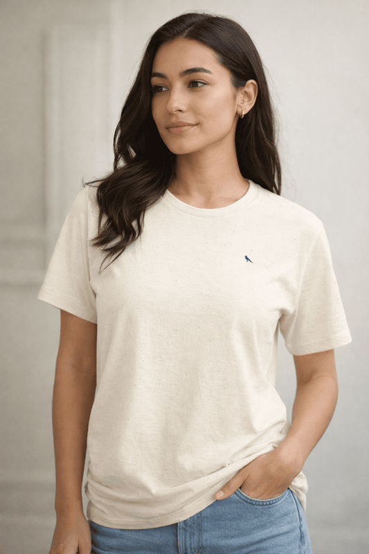 Woman wearing a plain white t-shirt with an embroidered bluebird on a neutral background