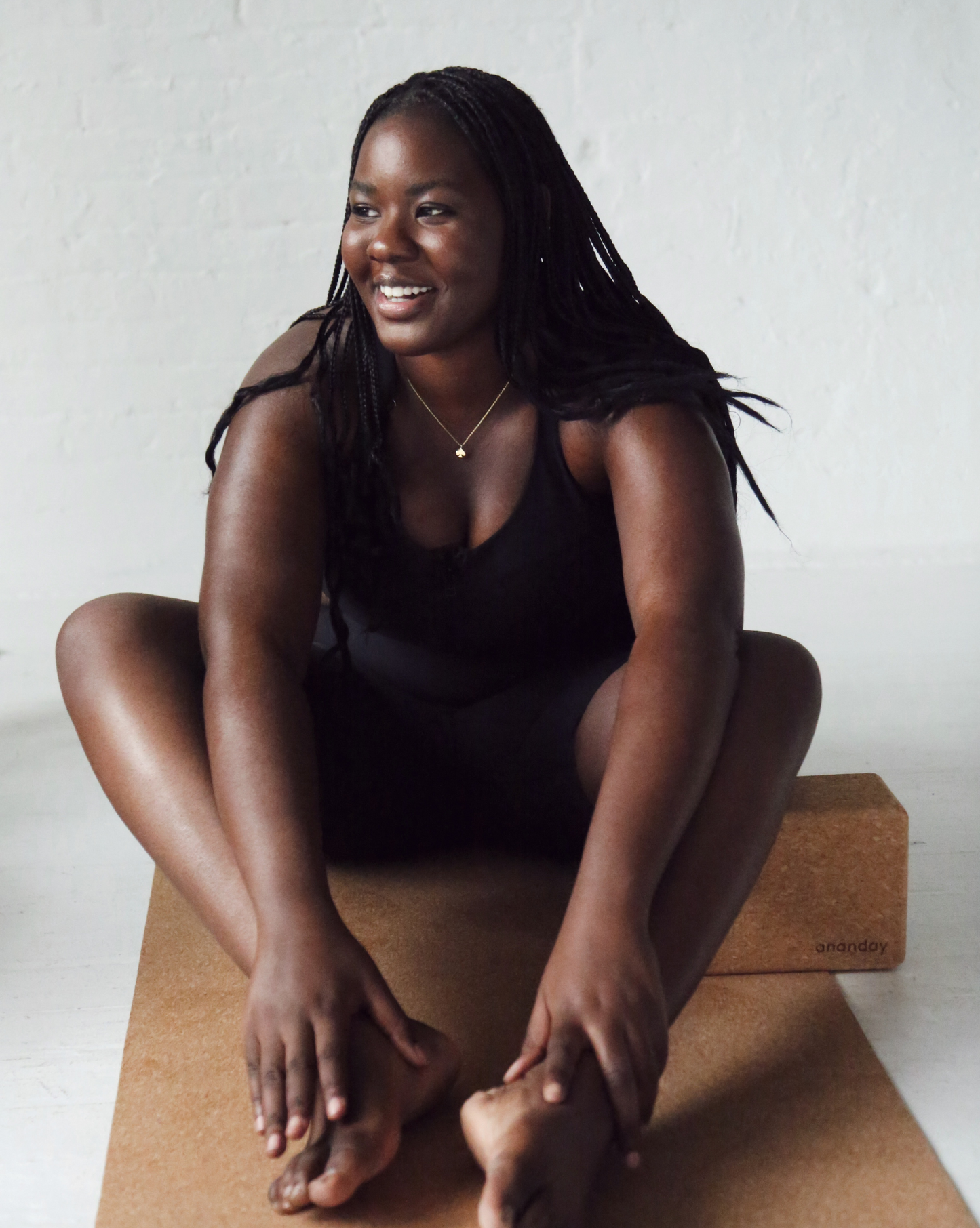 Woman sitting on a cork yoga mat with a white background ecofriendly product @shoppurpleumbrella