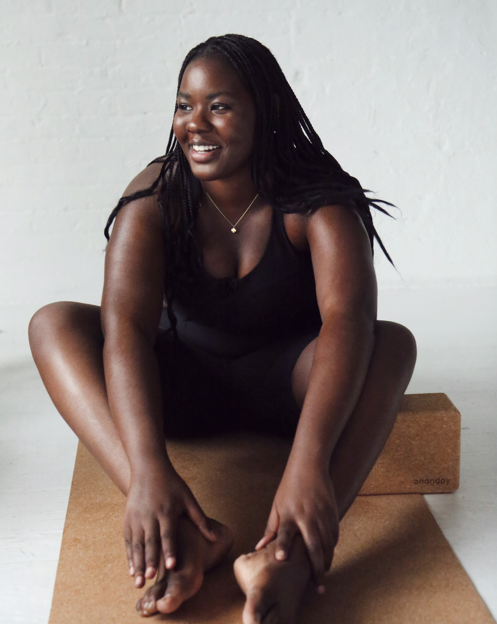 Woman sitting on a cork yoga mat with a white background ecofriendly product @shoppurpleumbrella