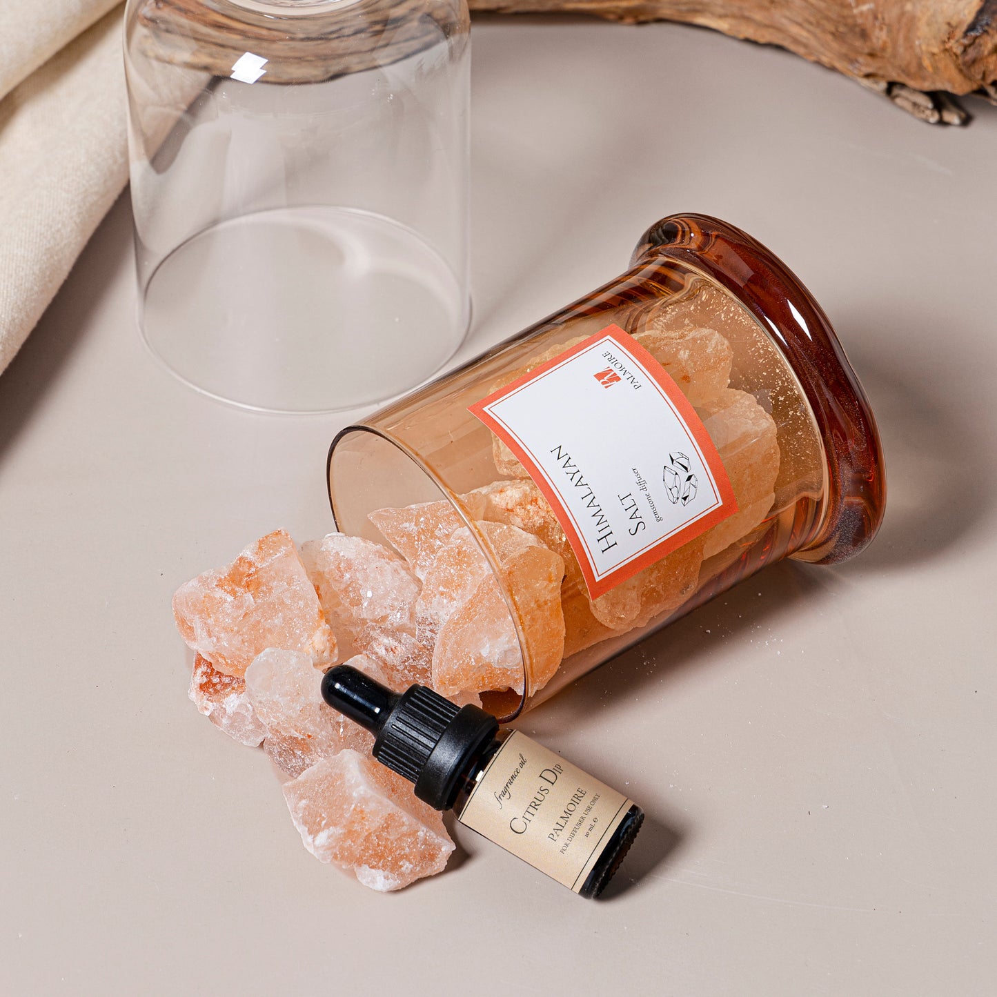 Glass container with crystals and a dropper bottle on a neutral surface