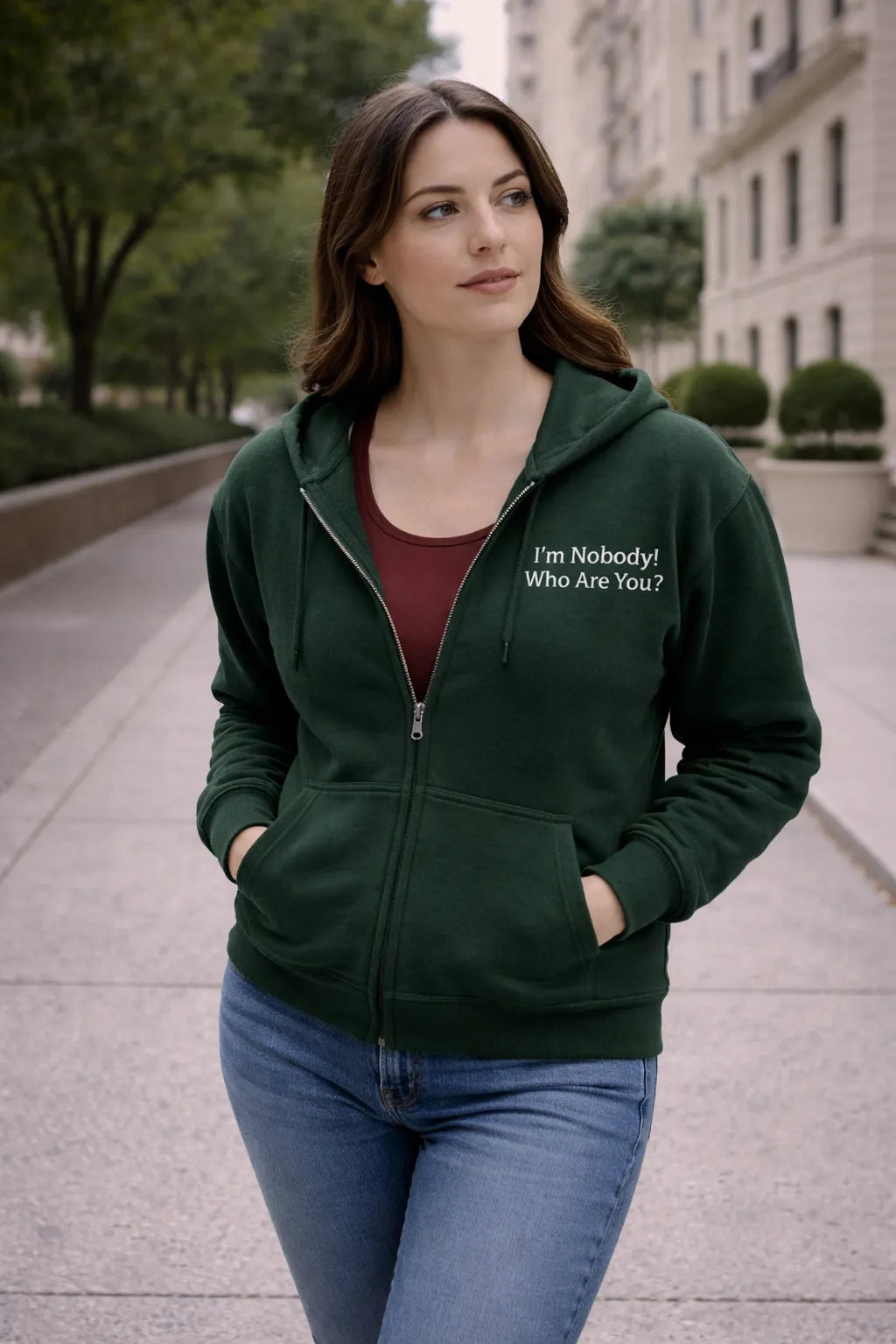 Woman wearing a green hoodie with embroidered Emily Dickinson quote on a city street