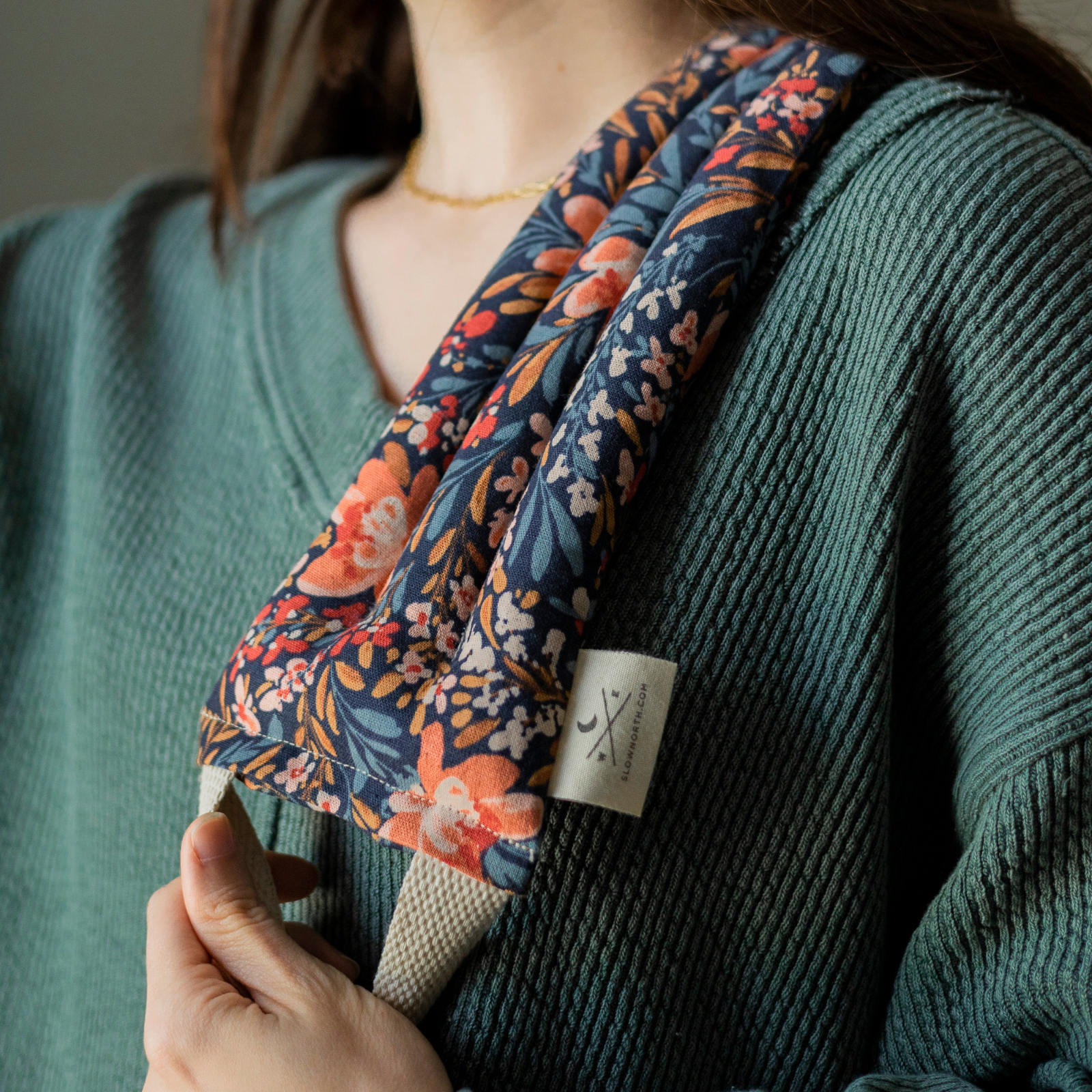 Person wearing a floral-patterned headband with a brand tag, against a neutral background