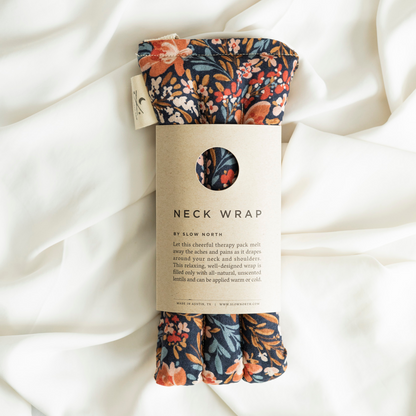 Neck wrap with floral pattern on packaging against a white fabric background