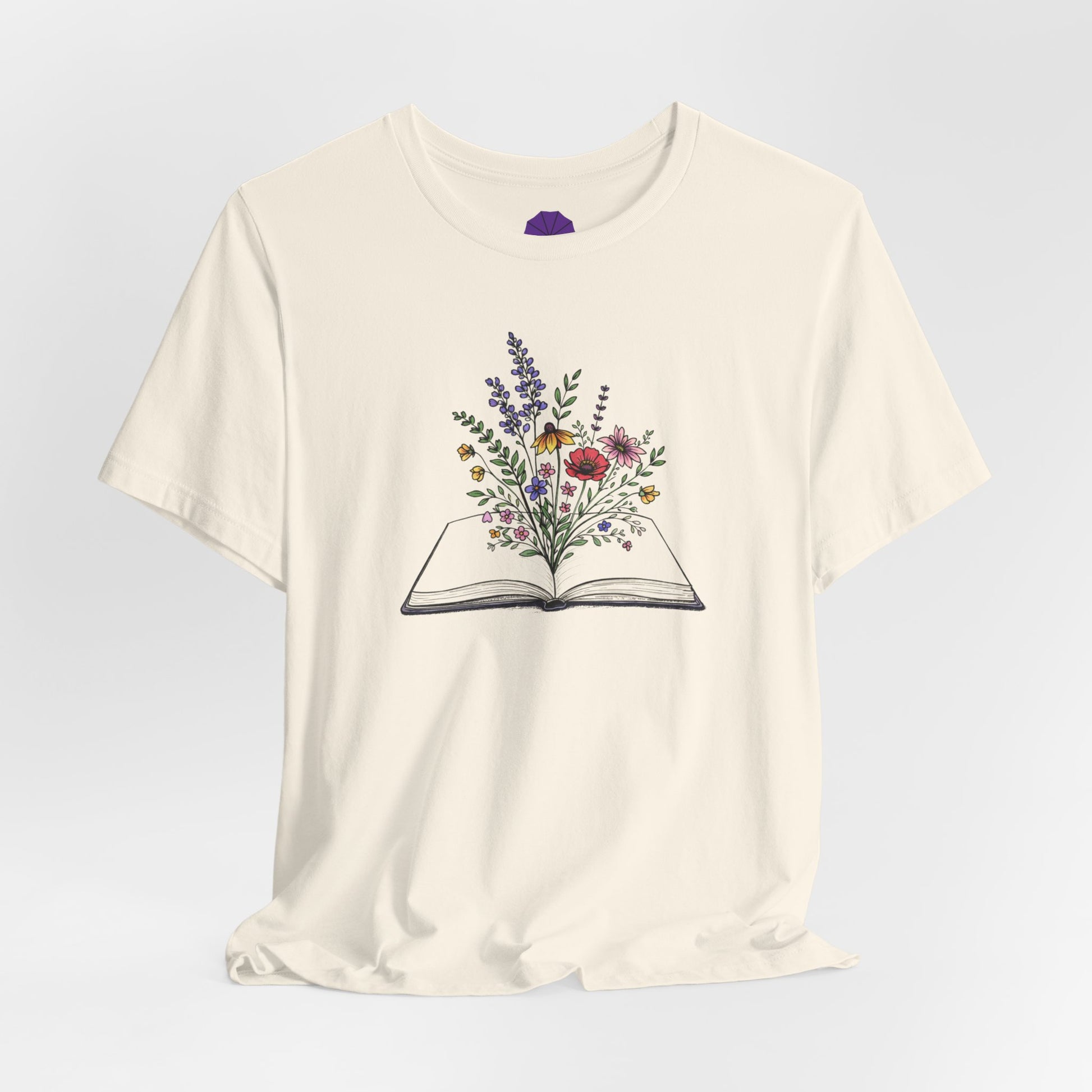 White t-shirt with an open book and floral design on a light gray background
