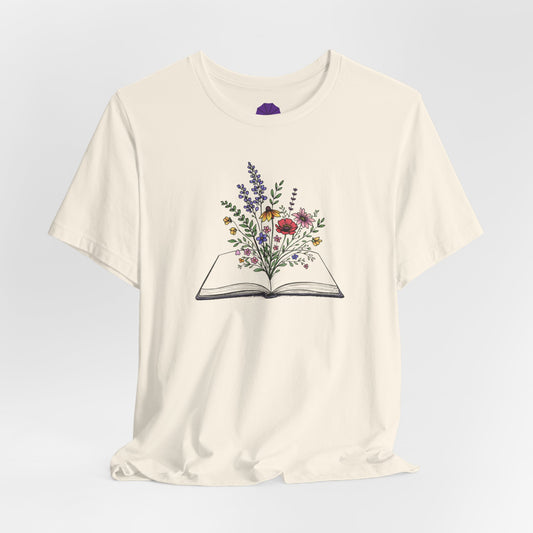 White t-shirt with an open book and floral design on a light gray background