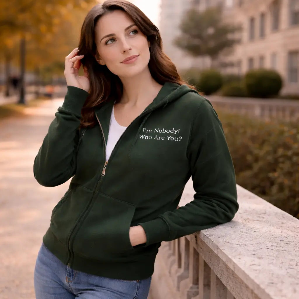 Woman wearing a green hoodie with embroidered Emily Dickinson quote, standing outdoors.