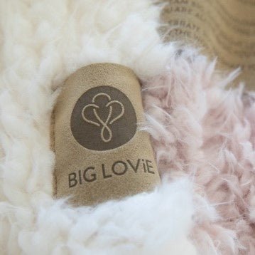 Heart-shaped pillow with 'BIG LOVIE' branding on a fluffy white surface