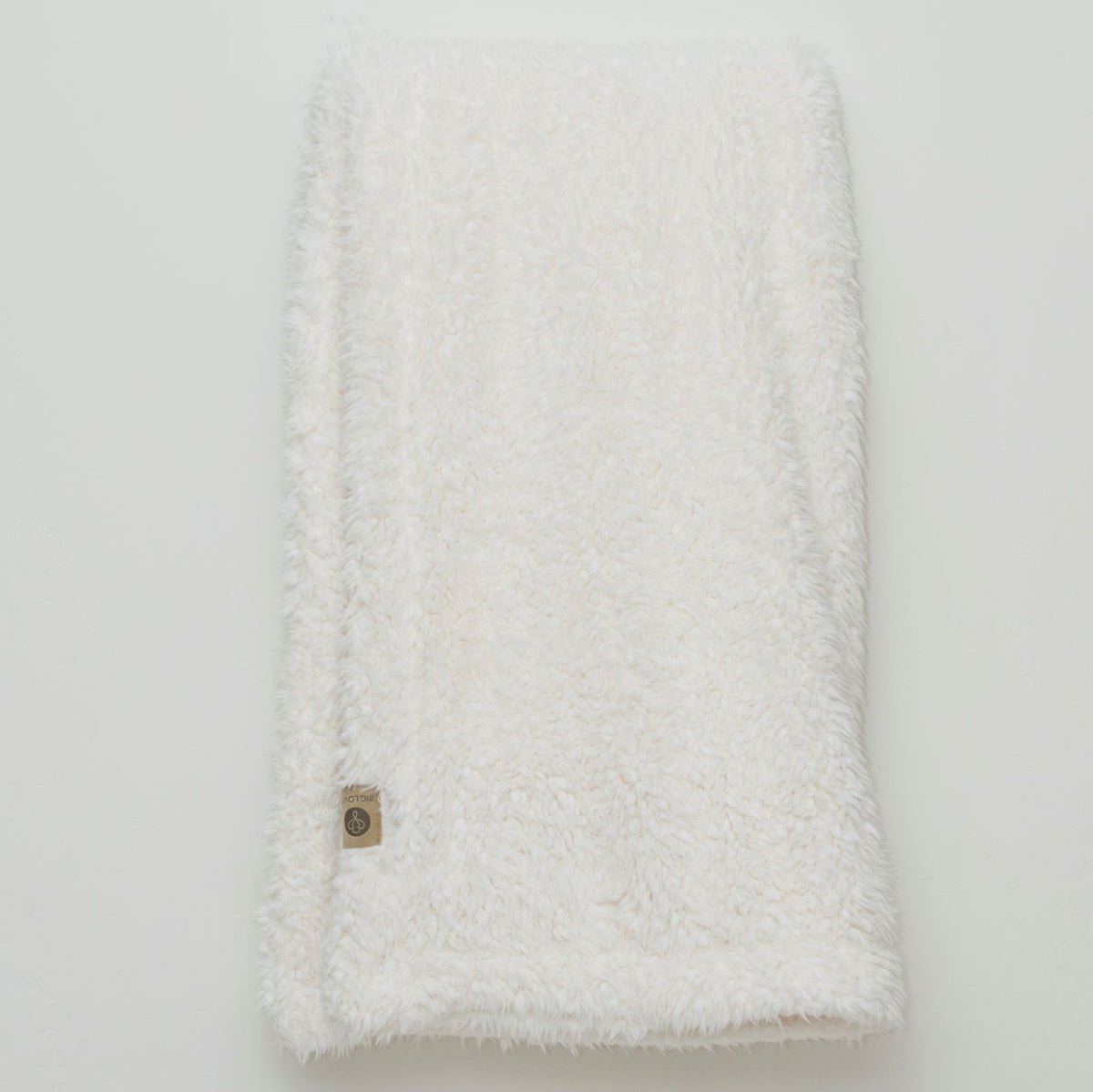 White textured blanket with a button on a light gray background