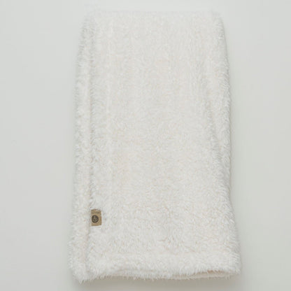 White textured blanket with a button on a light gray background