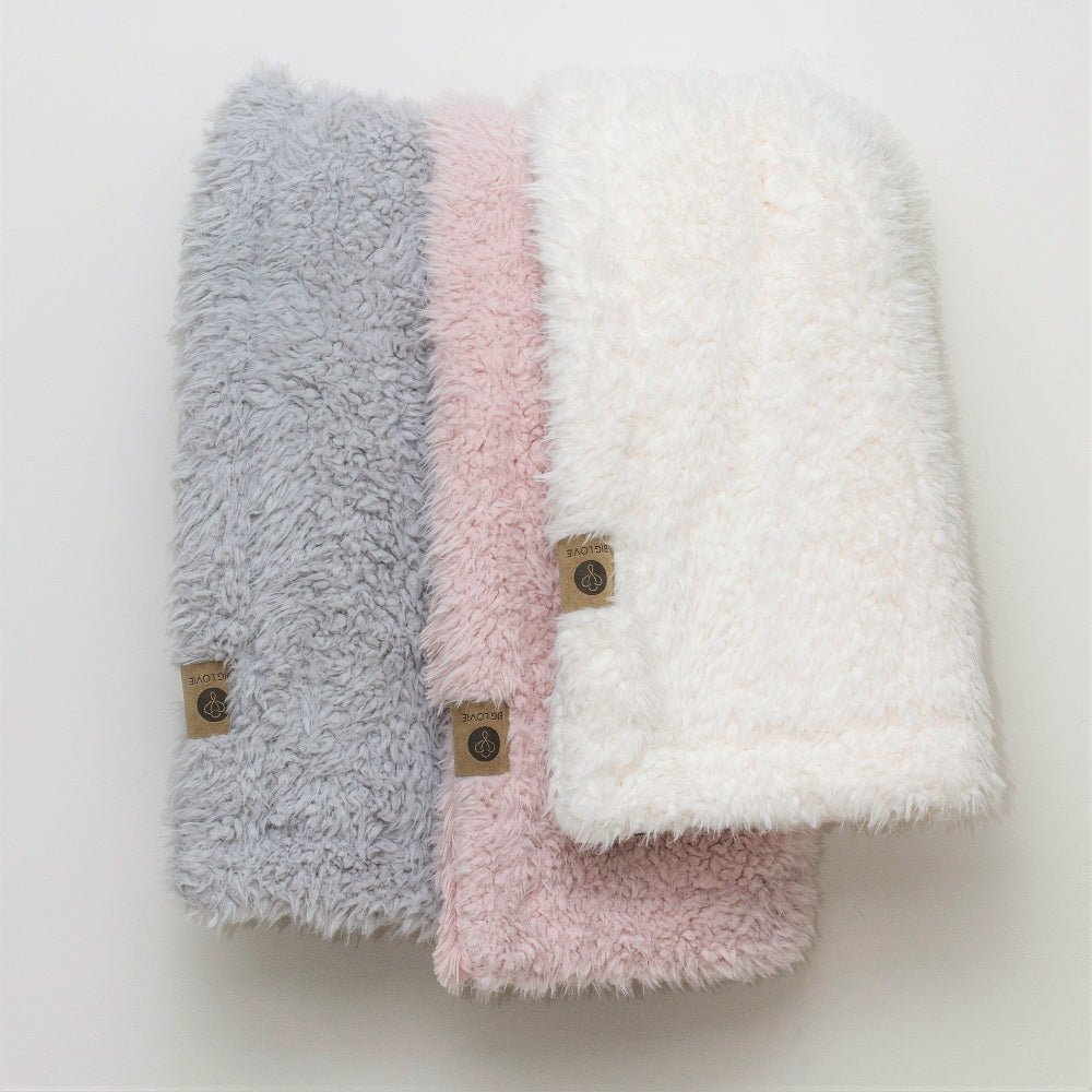 Three fluffy beanies in gray, pink, and white on a light background