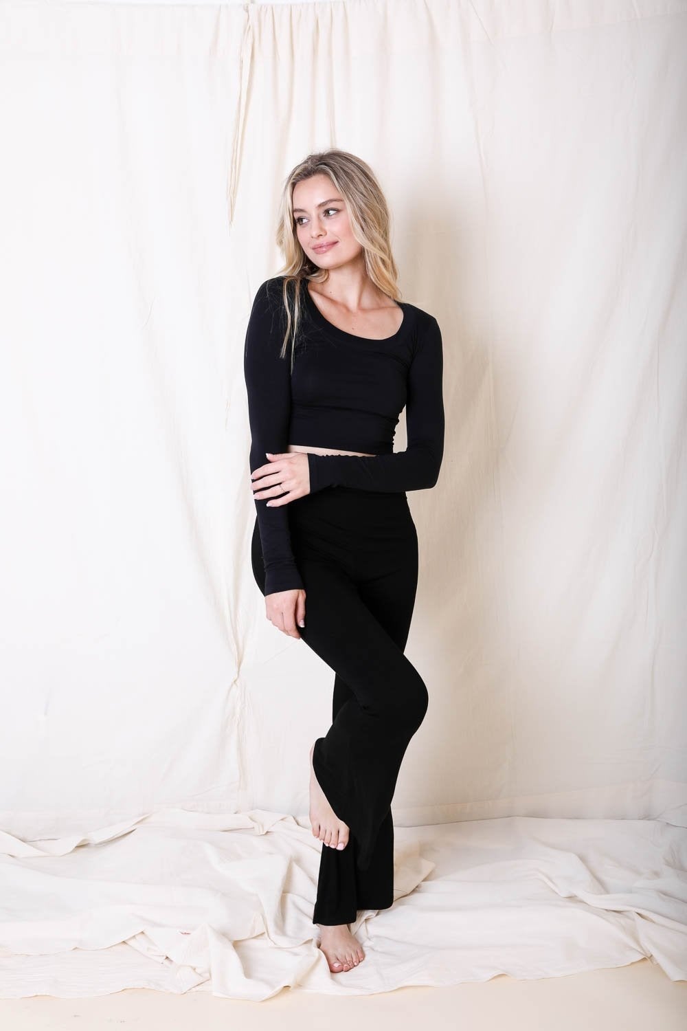 Woman wearing a black outfit standing against a white curtain