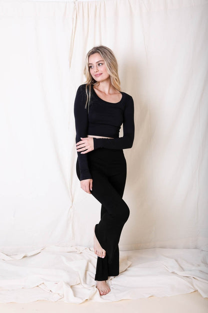 Woman wearing a black outfit standing against a white curtain