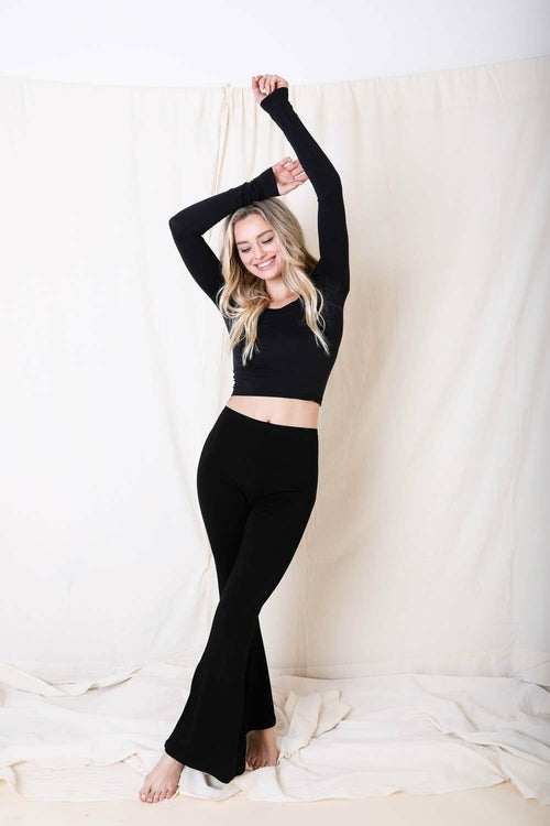 Woman in black outfit posing against a white curtain
