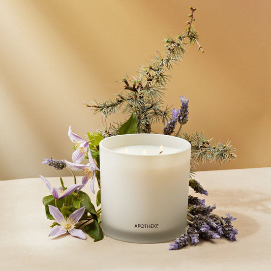 White candle labeled 'Apotheke' with lavender and greenery on a beige background