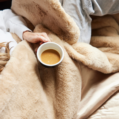 Close-up of plush Camel faux fur with a hand holding a cup of coffee