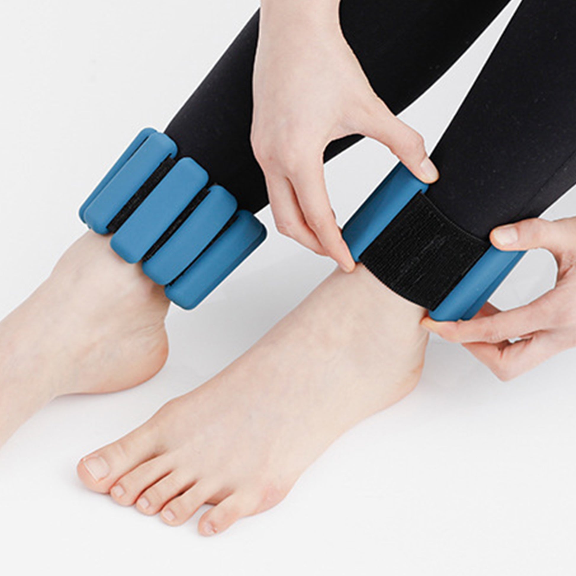 Woman fastening blue silicone weight bangle around ankle showing adjustable Velcro strap