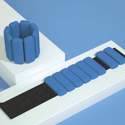Blue silicone wrist and ankle weight bangles with adjustable Velcro strap on white styled surface
