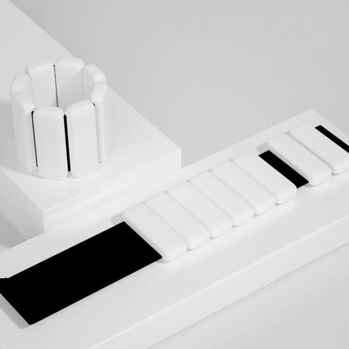 White silicone wrist and ankle weight bangles with adjustable Velcro strap on white styled surface