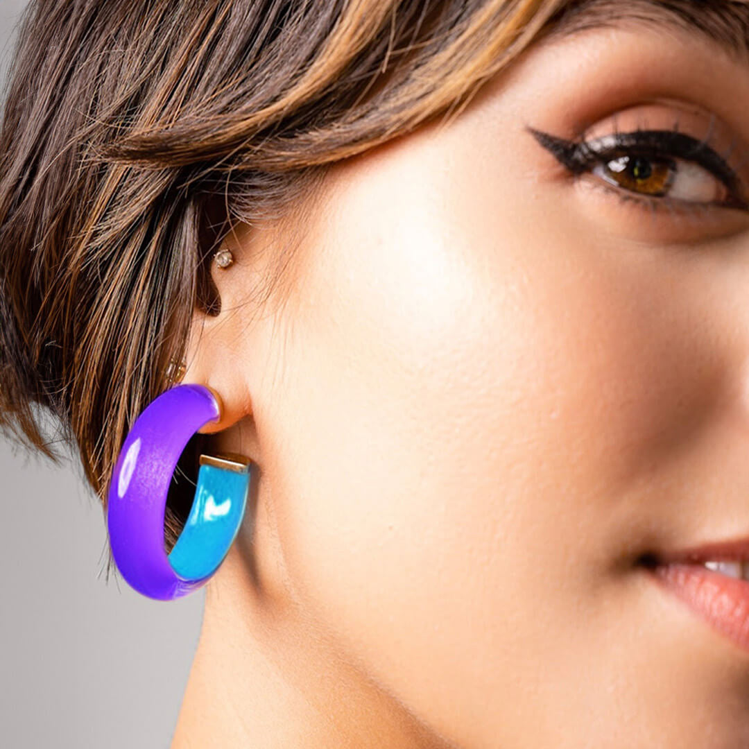 Close-up of a woman wearing a purple and blue Lucite hoop earring