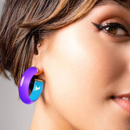 Close-up of a woman wearing a purple and blue Lucite hoop earring